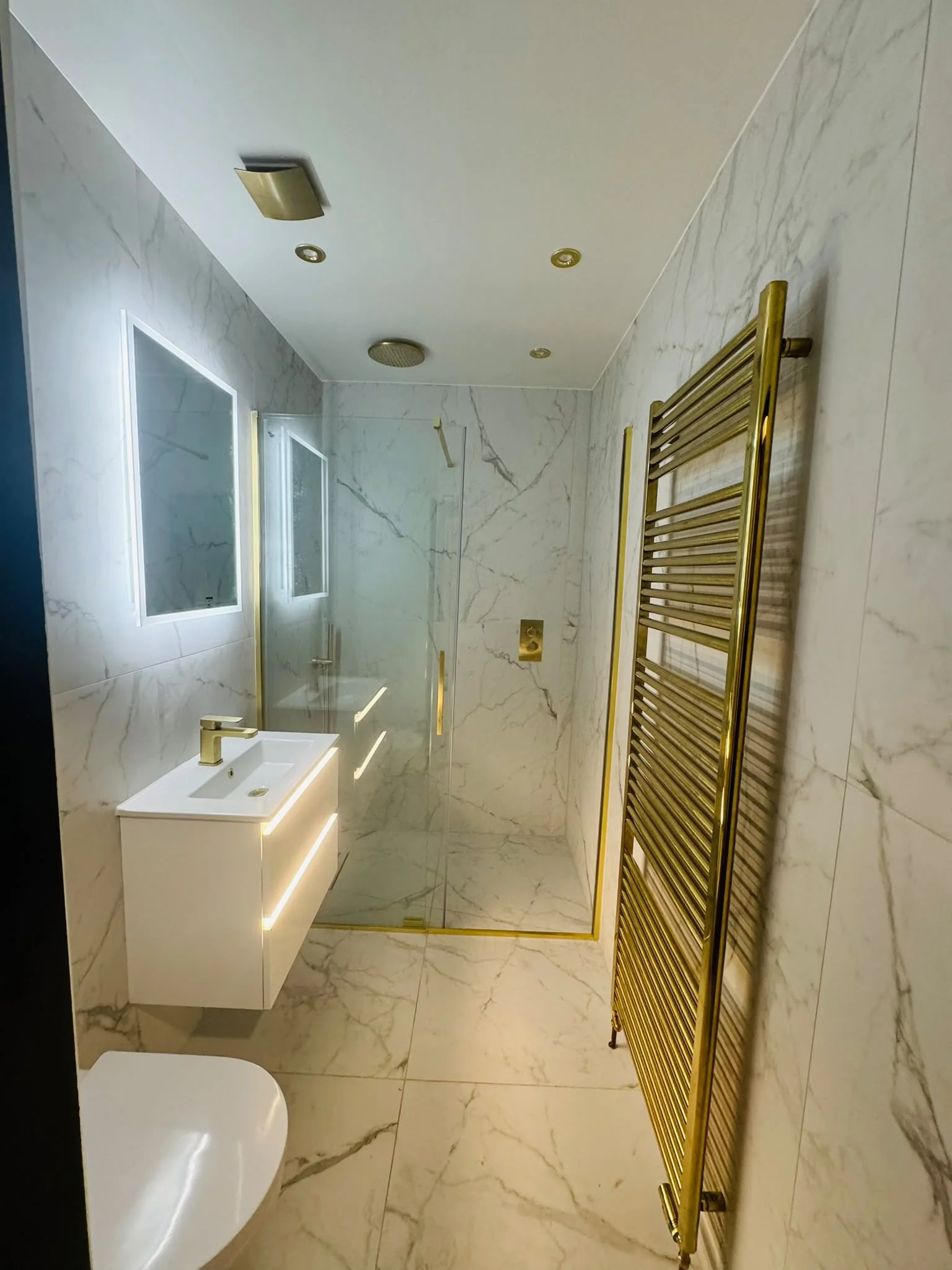 Completed marble-effect shower room with gold fittings and heated towel rail in Motherwell