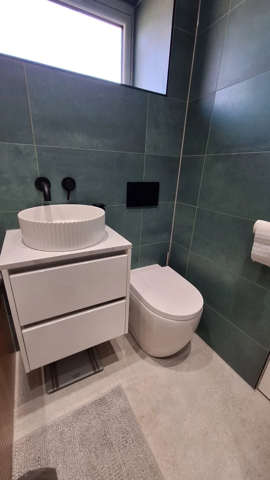 Completed green tiled bathroom with countertop basin and toilet in Coatbridge