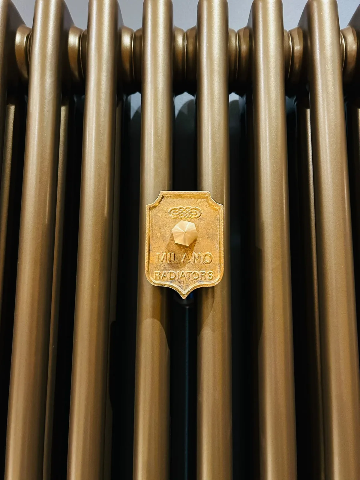Close-up of a Milano gold designer radiator and badge